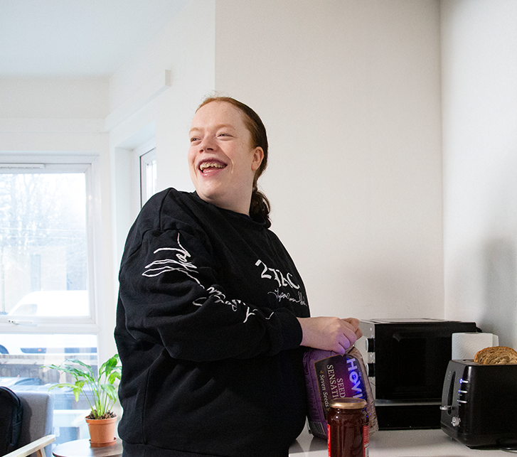 A smiling service user preparing her lunch in a bright kitchen