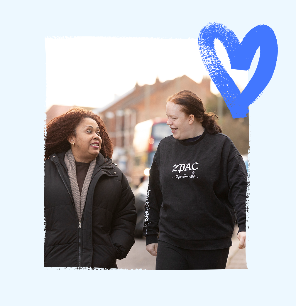 Service user and a support worker walking together down a bustling street towards shops