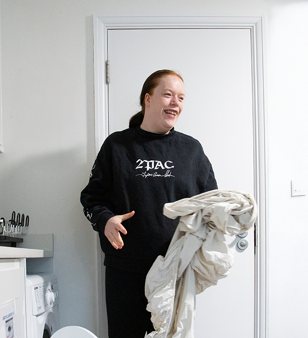 Service user standing next to a washing machine, actively engaged in doing laundry.
